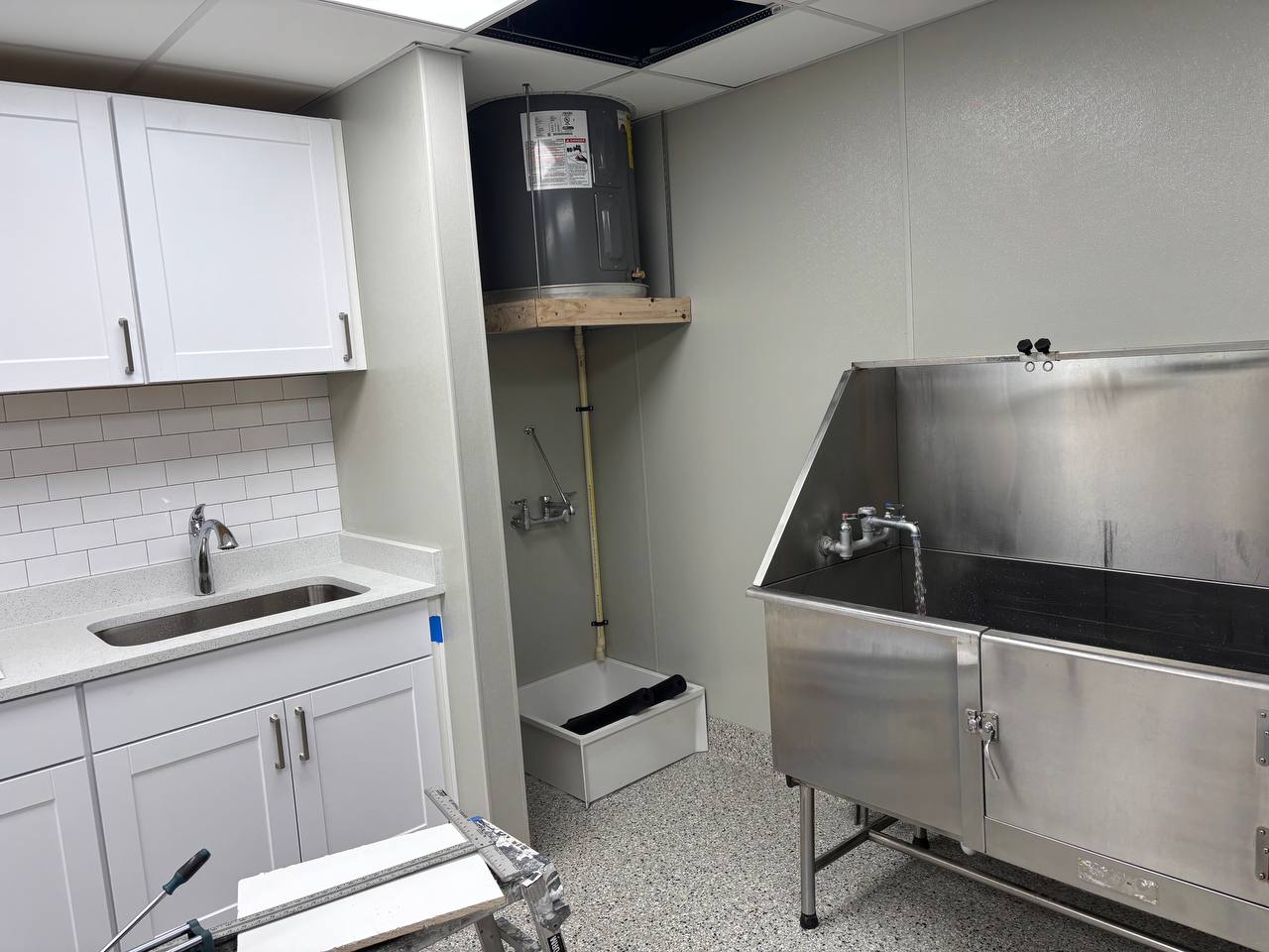 Finished commercial wash room with sink, stainless tub, and tank water heater